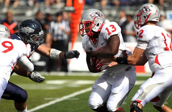 Nevada defender Jack Reynoso, rear left, reaches in as New Mexico quarterback B.R. Holbrook (12) hands off to James Wright (13) in Reno, Nev., on...